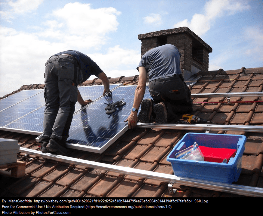 Workers installing solar panels on a roof