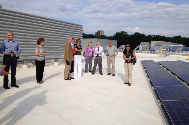 people standing by solar panels on a high school.