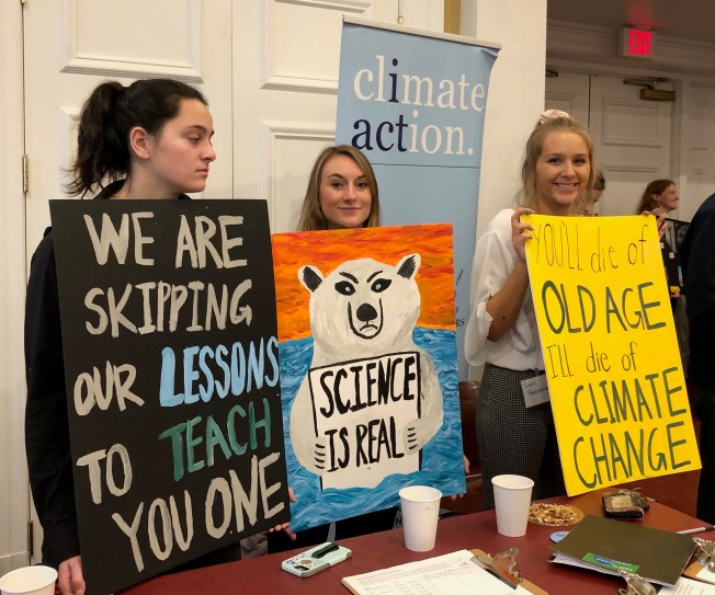 Three young women holding climate action signs