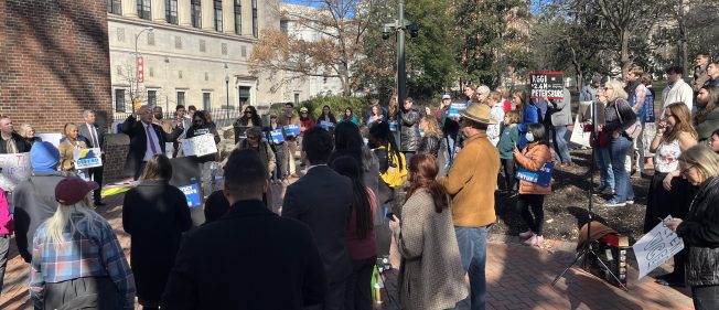 People gathered in a square listening to speakers.