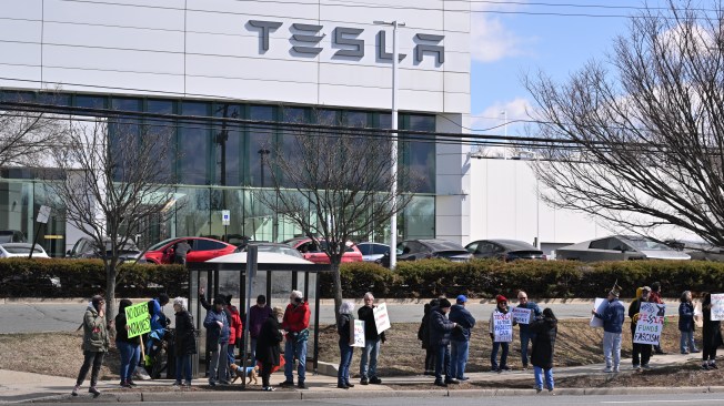 Protesters in front of a Tesla building.